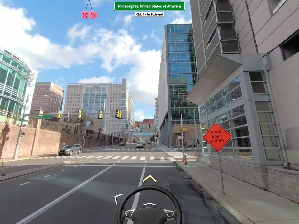 Internet Roadtrip street-view driving scene in Philadelphia, showing city streets, traffic lights, a road-work sign, and a steering wheel interface.