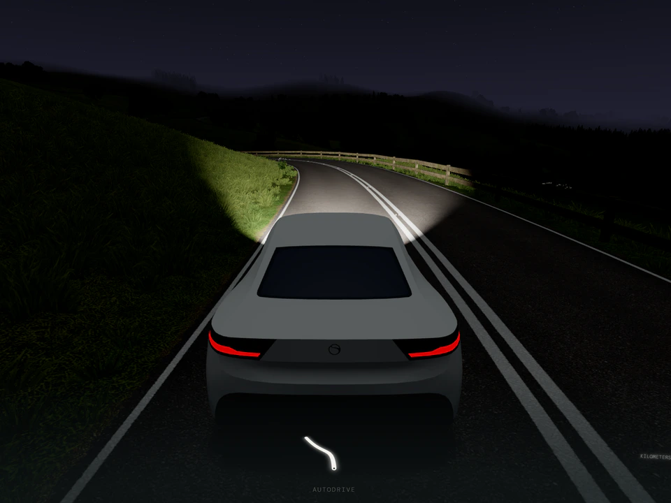 Nighttime driving scene viewed from behind a gray car on a winding two-lane road, with headlights illuminating the curve ahead and an “Autodrive” indicator below.